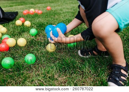 Colored Plastic Toy Balls Spilled In The Grass. Boy Gethering Blue Balls. Baby Birthday Party Activi