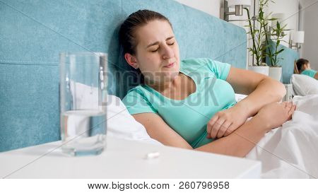 Portrait Of Young Woman Suffering From Stomach Ache Lying In Bed