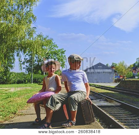 Adorable Little Children On A Railway Station, Waiting For The Train With Vintage Suitcases. Traveli
