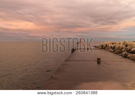 A Lighthouse Pier On Lake Michigan At Sunset With Pink Clouds Reflected In The Water.  Sheboygan, Wi