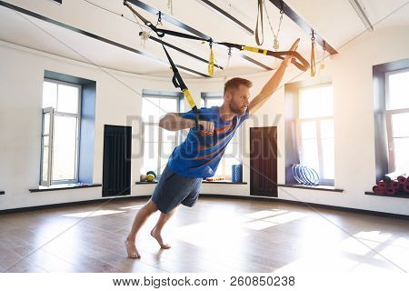Handsome Muscular Man Athlete Doing Exercise Alone With Fitness Belts In Modern Gym Club, Workout Si