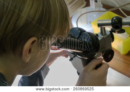 Young School Boy In Science Class, Looking Through The Microscope. Close-up Portrait Of A Side View.