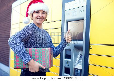 Woman With Santa Christmas Hat Client Using Automated Self Service Post Terminal Machine Or Locker T