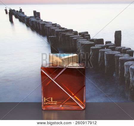 Kl Homme, Mens Fragrance, Large Perfume Bottle In Front Of The Picture Of A Groyne In The Sea