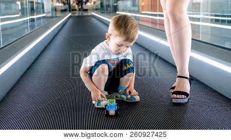 2 Years Old Toddler Boy Playing With Toys On Moving Walkway At Airport Terminal