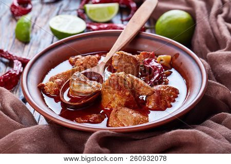 Carne Adobada Or Hearty Red Chile And Pork Stew In A Clay Bowl With Spoon On An Old Wooden Table Wit