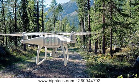 A Drone Hovers On A Woodland Path. The Drone Is In Mid Flight And Surrounded In A Lush Pine Forest I