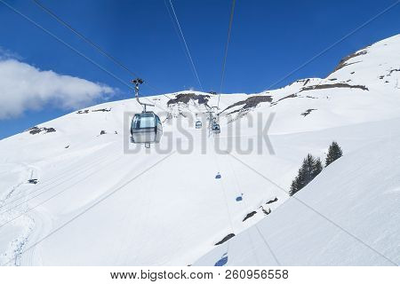 Gondola Lift ( Cable Car ) With Tower And Station Over White Snow And Blue Sky Of Mountain Alps, Tra