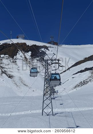 Gondola Lift ( Cable Car ) With Tower And Station Over White Snow And Blue Sky Of Mountain Alps, Tra