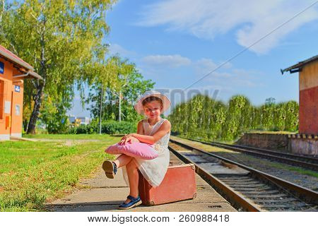 Cute Happy Girl Holding Plush Toy On A Railway Station, Waiting For The Train With Vintage Suitcase.