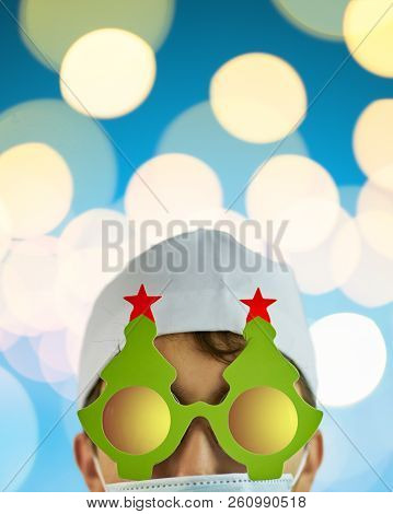 Crazy Physician In Christmas Tree Glasses With Red Stars And White Coat On Blue Background With Brig