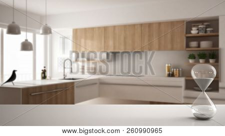 White Table Or Shelf With Crystal Hourglass Measuring The Passing Time Over Blurred Modern Kitchen W