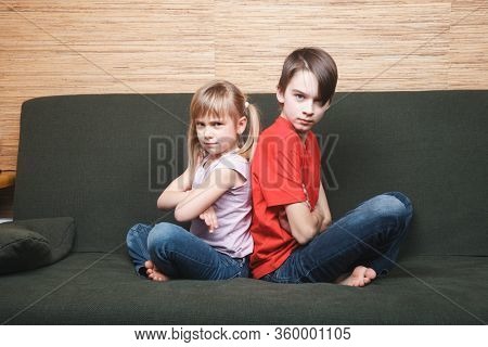 Frustrated siblings sittng on sofa stuck at home being in self-isolation. Quarantine and lockdown protective measures against spreading of coronavirus pandemic disease