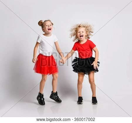 Active Frolic Kids Girls Friends Sisters In Red And Black Fatin Skirts And T-shirts Are Jumping Play