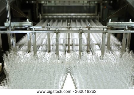 Visual Control Of Ampoules With Medicine. A Woman Works On An Ampoule Production Line. Sterile Bottl