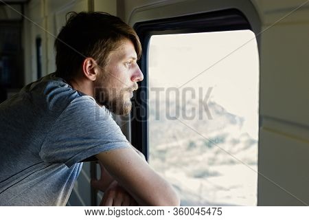 Middle Plane Portrait Of A Handsome Young Caucasian Man With A Beard, Looks Outside Of The Train's W