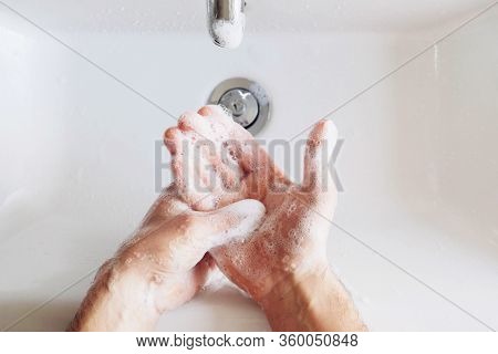 Man Cleaning His Hands Using Liquid Disinfectant Soap And Water In Bathroom.