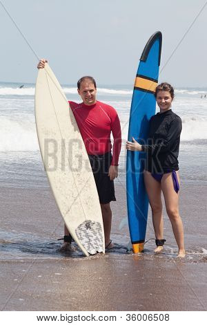 คนหนุ่มสาวกับ surfboards ที่ยืนอยู่ในน้ำ