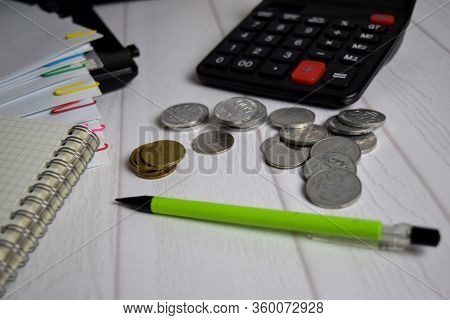 Calculator And The Stack Of Coint Isolated On Office Desk. Calculating Salary Or Tax Concept