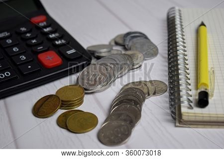 Calculator And The Stack Of Coint Isolated On Office Desk. Calculating Salary Or Tax Concept