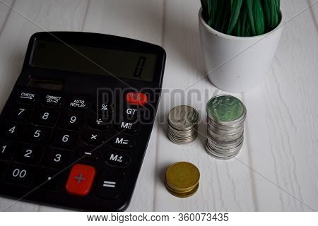 Calculator And The Stack Of Coint Isolated On Office Desk. Calculating Salary Or Tax Concept