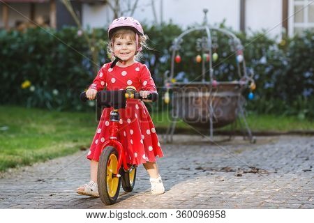Cute Little Toddler Girl In Safety Helmet Riding On Run Balance Bike. Happy Healthy Lovely Baby Chil