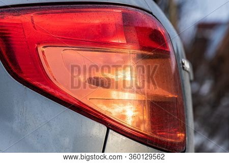 Bright Wet Red Fara Of Car With Water Drops And Yellow Sunset Reflection