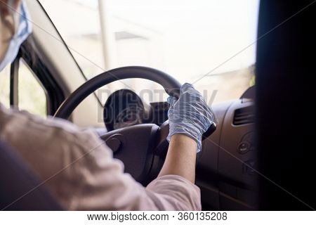 A Young Woman In A Surgical Face Mask And Gloves Driving The Car During Coronavirus Pandemic. A Fema