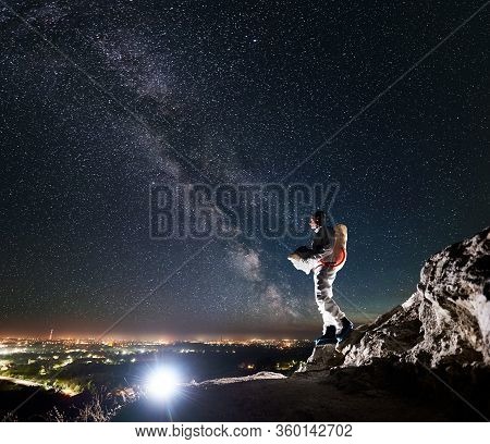 Cosmonaut Standing On Rocky Hill Under Beautiful Night Sky With Stars And Milky Way. Space Traveler 