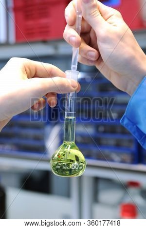 Conducting A Chemical Experiment In A Laboratory. Colored Flasks With Chemical Reagents. Many Glass 
