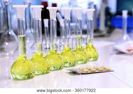 Conducting A Chemical Experiment In A Laboratory. Colored Flasks With Chemical Reagents. Many Glass 