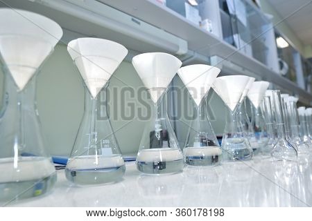 Conducting A Chemical Experiment In A Laboratory. Colored Flasks With Chemical Reagents. Many Glass 