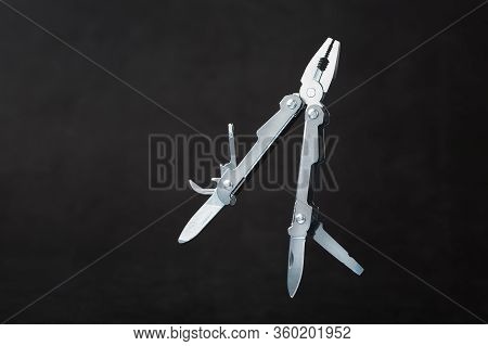 Multi-functional Tool On A Black Textural Background.