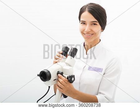 Portrait Of A Mixed Race Gynecologist Sitting In An Office Near A Colposcope. Gynecologist Professio