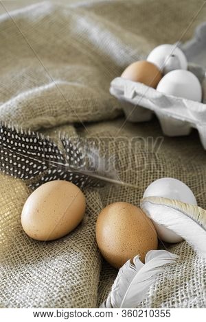 Different Coloured Eggs With Feathers Lying On A Jute Bag