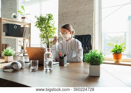 Meeting. Woman Working In Office Alone During Coronavirus Or Covid-19 Quarantine, Wearing Face Mask.