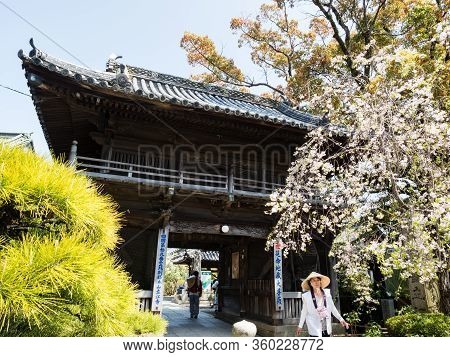 Komatsushima, Japan - April 4, 2018: Pilgrim Walking Out Of The Gate Of Tatsueji, Temple Number 19 O
