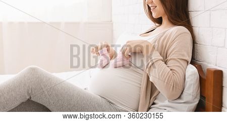 Expecting For Firstborn. Pregnant Woman Playing With Small Booties And Her Belly, Panorama, Empty Sp