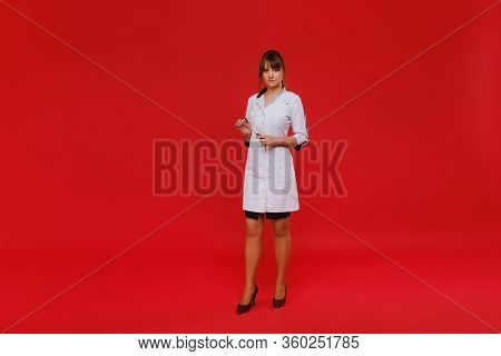 Beautiful Girl Doctor Holds A Reflex Hammer And Smiles At The Camera Isolated On Red