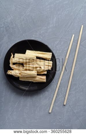 Fermented Soy Tofu Yuba Skin With In The Center Of The Frame On A Brown Plate On A Gray Neutral Back