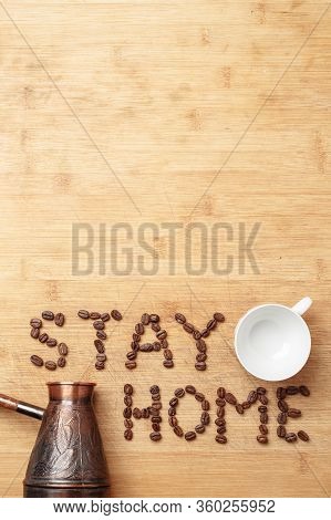 The Slogan Stay Home As Inscription Lined With Roasted Coffee Beans On A Homemade Wooden Cutting Boa