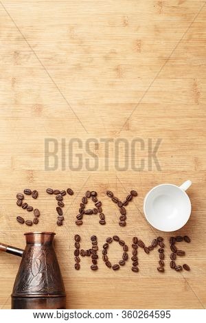 The Slogan Stay Home As Inscription Lined With Roasted Coffee Beans On A Homemade Wooden Cutting Boa