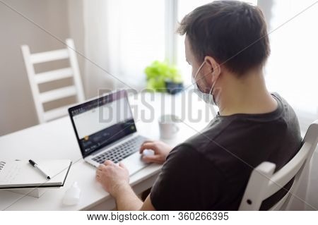 Men Wearing Disposable Medical Face Mask Working Online On Laptop Computer At Home During Coronaviru