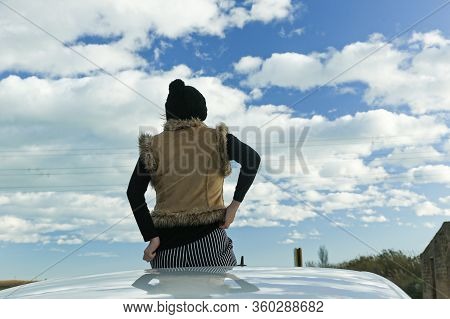 Woman Sitting In A Car White With Her Back To The Clouds