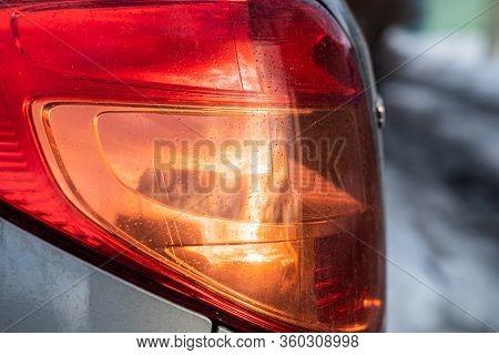 Bright Wet Red Fara Of Car With Water Drops And Yellow Sunset Reflection