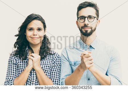 Excited Couple Hoping For Luck, Making Prayer Gesture. Young Woman In Casual And Man In Glasses Stan