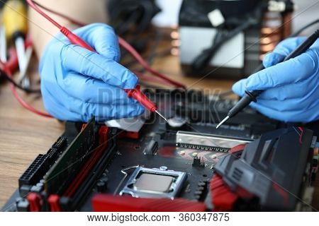 Close-up Of Middle-aged Man Measuring Electrical Voltage. Technician Male Repairing Computer Mainboa