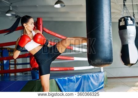 Female Boxer Workout High Kick On The Punching Bag In Gym. Sport Concept
