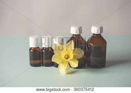 Bottles Of Medicine Lined Up On A White Background. Beautiful Yellow Flower, Spring. Chemical Experi