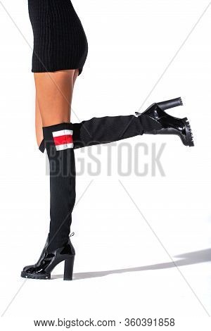 The Girl Stands In Black Hessian Boots On The Feet Of A Model On A White Background With Shadows. Ja